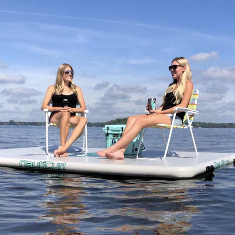 NautiPad Inflatable Swim Mat on the water with 2 adults sitting on individual beach chairs atop the mat.
