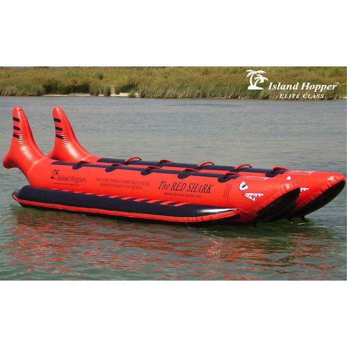 Side view of the Island Hopper 10 Person Red Shark Banana Boat sitting unoccupied on the lake. 