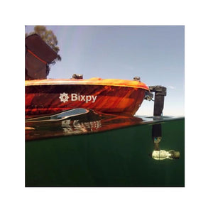 Bixpy Jet Thruster is used with a Bixpy Universal Rudder Adapter on an orange kayak.  The view is partially underwater and you can see the side view of the light grey, almost white Bixpy Jet Thruster.