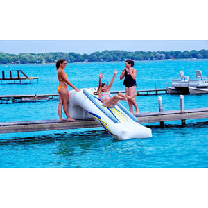 Young girl sliding down a Rave Inflatable Dock Slide while 2 adults stand by and watch here slide into the lake from the dock.  