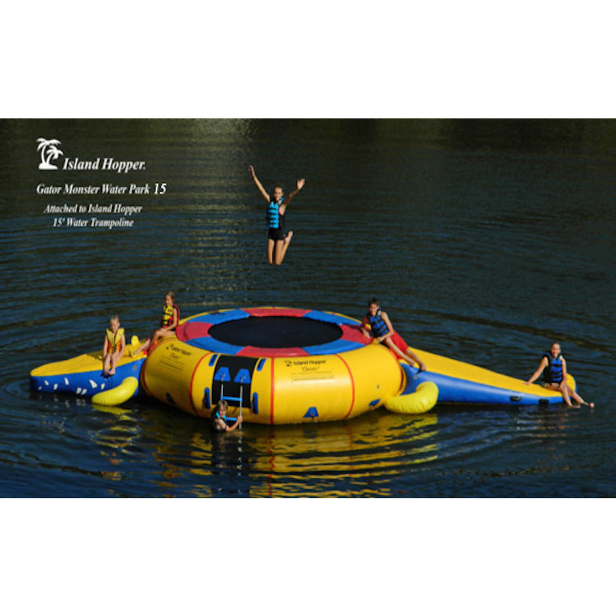 Yellow Island Hopper 15' Gator Monster Water Trampoline Water Park with blue and red trim on a white background.  4 Kids sitting on the inflatable water park and 1 kid jumping on the water trampoline. 