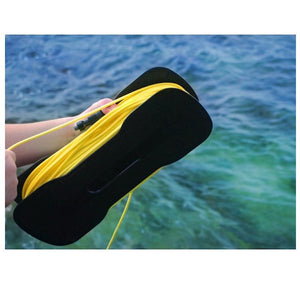 The yellow tether of the Chasing Gladius Mini Underwater Drone is wrapped around a black piece to store the tether.  A boy is holding it over the water, close up view.