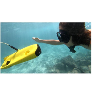 Close up view of a snorkeler swimming up to the front and looking in the camera of the yellow Chasing Gladius Mini Underwater Drone.  The little girl is waving and reaching out to touch the top edge, the water is clear and light blue.