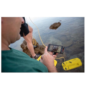 A man uses his phone to control the Chasing Gladius Mini Underwater Drone out at sea.  The Gladius Underwater drone for sale is on the surface of the water.