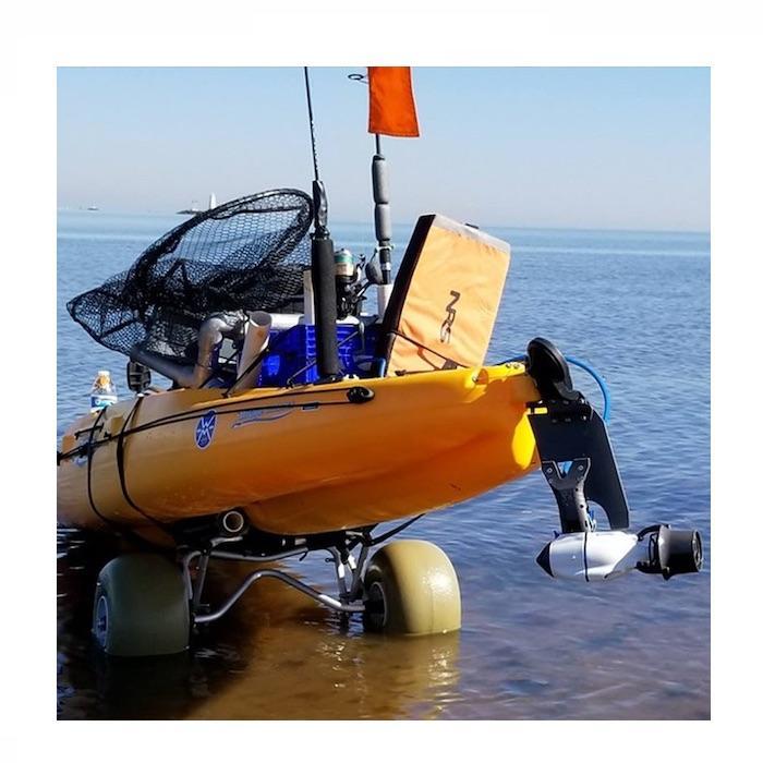 View of the back of an orange Hobie kayak on a 2 wheel cart about to go into the ocean.  The Bixpy Hobie Twist &amp; Stow Kayak Rudder Adapter is attached on the back.