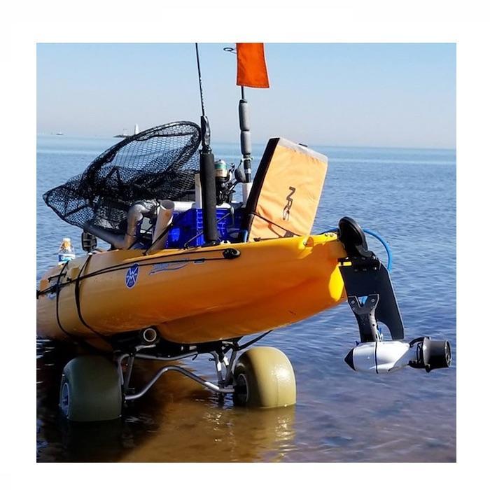 View of the back of an orange Hobie kayak on a 2 wheel cart about to go into the ocean.  The Bixpy Hobie Twist & Stow Kayak Rudder Adapter is attached on the back.