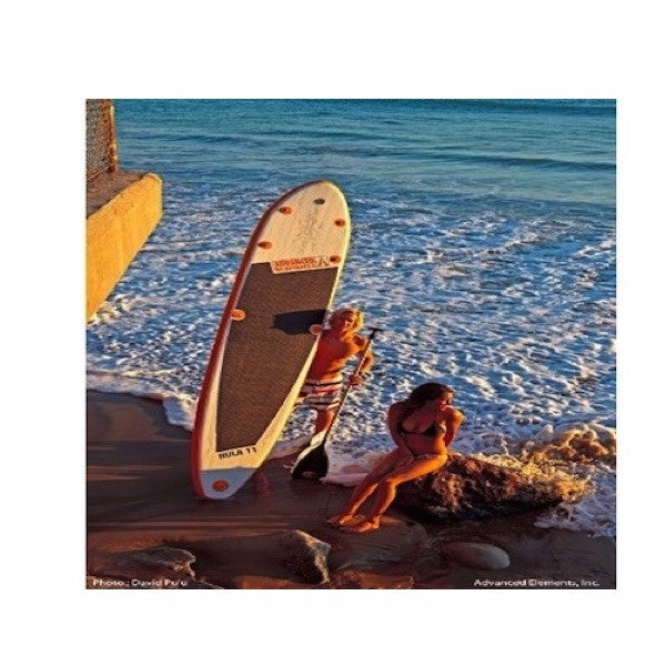 Orange and White Advanced Elements Hula 11 Inflatable SUP out of the ocean, standing on the beach. 