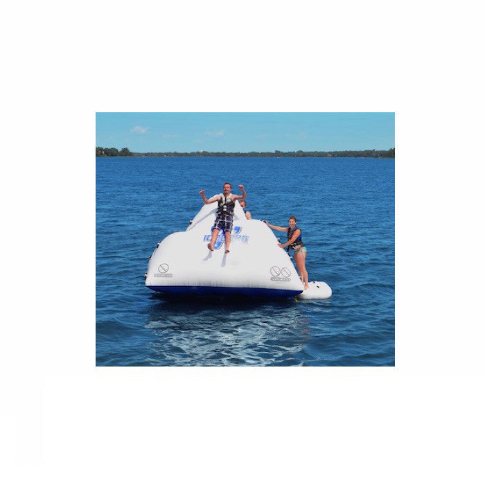 Guy sliding down a white Rave Floating Inflatable Iceberg 7 in the middle of the lake. 