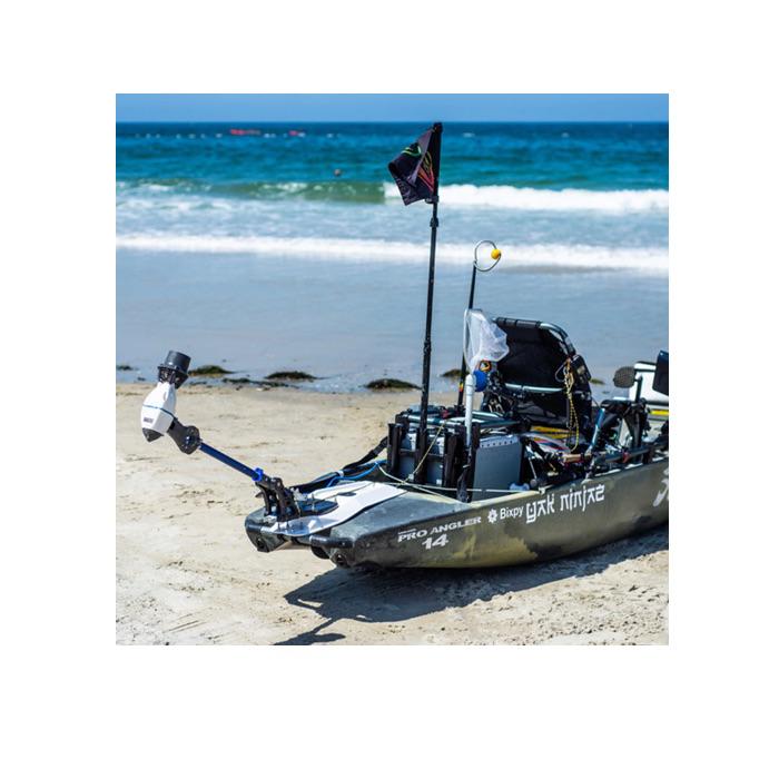  A kayak sits on the beach just outside the ocean waves running up the beach.  The Bixpy Kayak Jet Motor Outboard Kayak Motor Kit is shown on the rear of a kayak using a Bixpy Power Pole Adapter.  The Bixpy Jet Thruster is at the end of the fully extended pro angler kayak adapter and up in the air.
