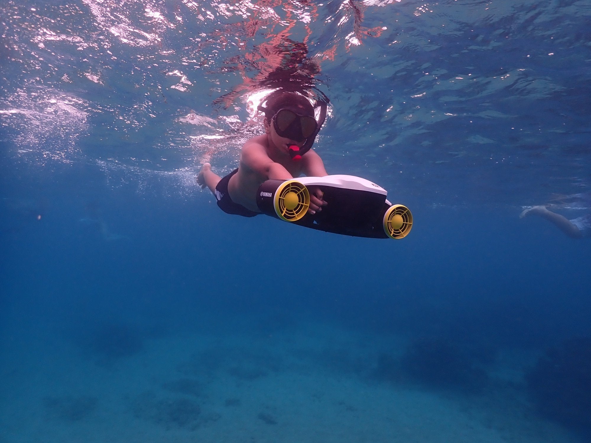 Front view of a young boy using his Yamaha Seawing II sea scooter to help proel his snorkeling adventures in these mostly clear waters.