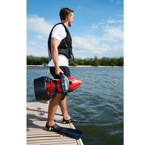 A young man stands on a dock with his Yamaha RDS200 Sea Scooter ready to jump in for some action.  He holds the red and black Yamaha RDS200 Seascooter in his right hand.