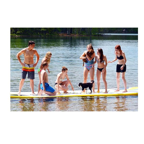 Rave Water Whoosh Floating Water Mat being used out on the lake with several kids playing with their dog on the durable inflatable water mat.