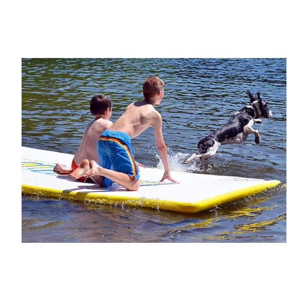 Rave Water Whoosh Floating Water Mat being used by 2 kids with their dog jumping off into the water.  You can see the white top of the inflatable water mat with yellow edges.