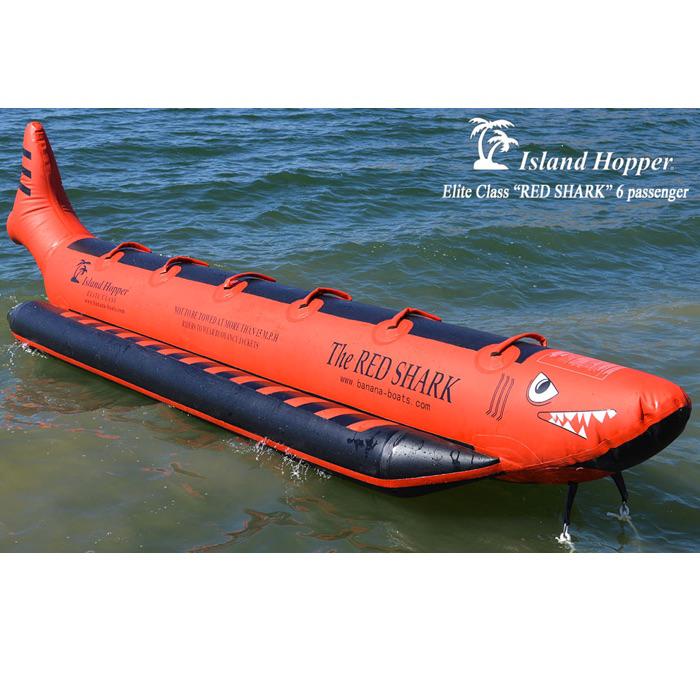 6 Person Island Hopper Red Shark Banana Boat Tube for Sale sitting in the ocean with no passengers. It is clean and intriguing look featuring red and black colors. 