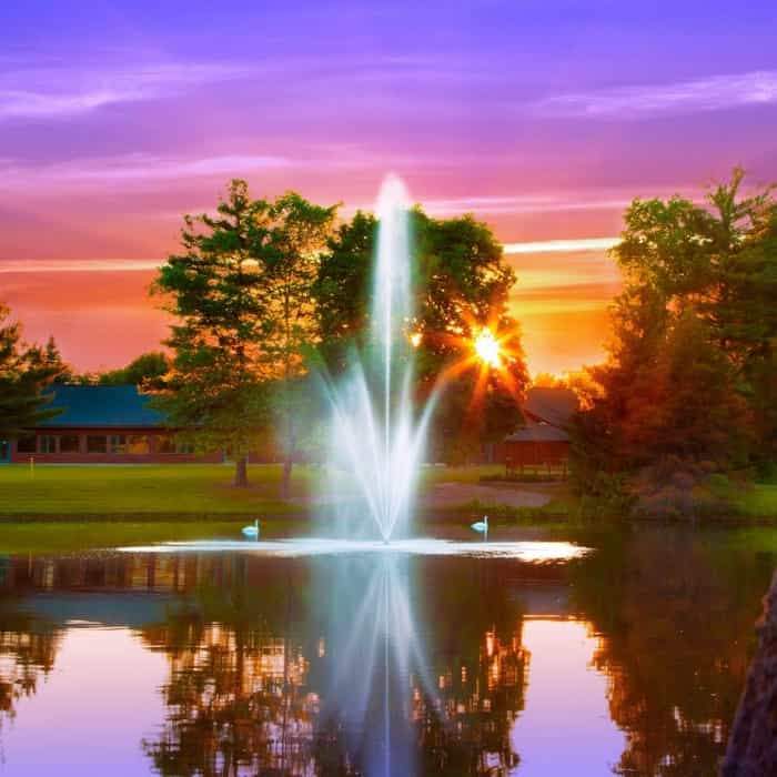 Scott Aerator Atriarch Pond Fountain creates a beautiful display against an orange and pink sky.  The Scott Aerator floating pond fountain sprays in the air with the sky's reflection also on the water. The floating fountain is the finishing touch for any water scape, unbelievable!