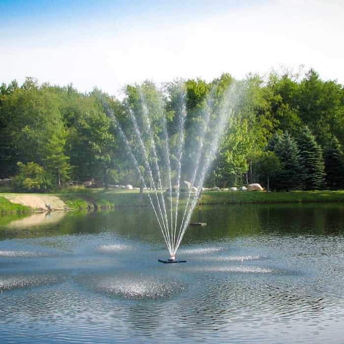 Scott Aerator Belcrest Pond Fountain sprays 30 feet high to showcase the beautiful floating fountain on the lake.  Dark Blue waters, light blue skies, and green trees all around.  Beautiful floating water fountains.