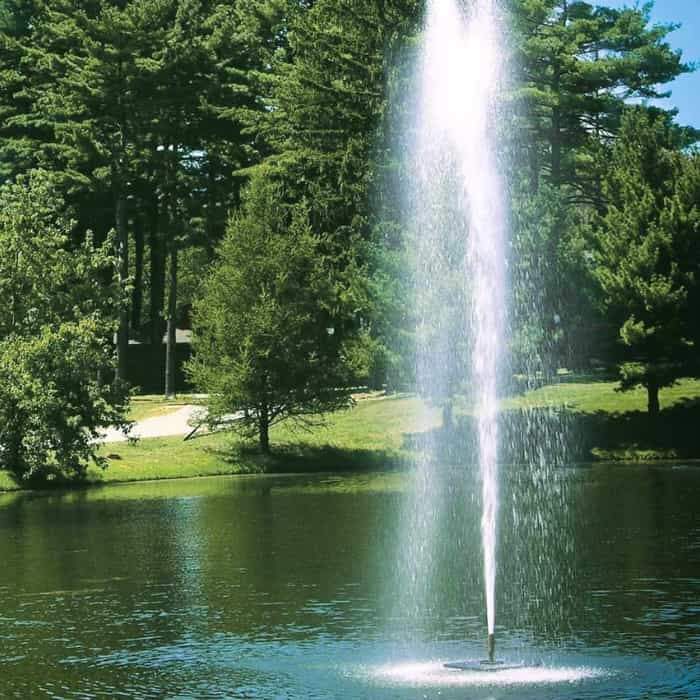 Scott Aerator Gusher Pond Fountain 1 1/2 Hp Floating Fountain sprays a wind resistant column of water 30ft in the air.  Shown here as a floating pond fountain in a park setting with evergreen trees around.