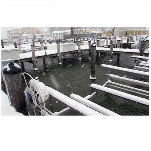 Docks in a marina are shown with a de-icer in use.  The water is not frozen in the wooden dock slips but is frozen away from the dock.