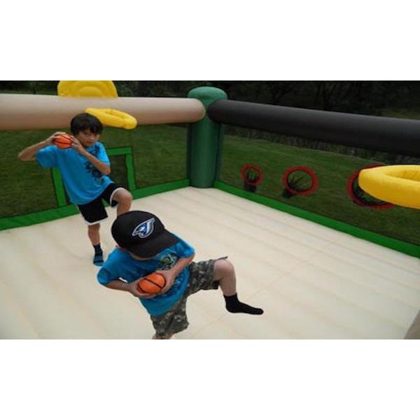 2 kids throwing balls in the ball toss of the Island Hopper Sports and Hops 5 Bounce House, standing on the tan bounce floor surface. 