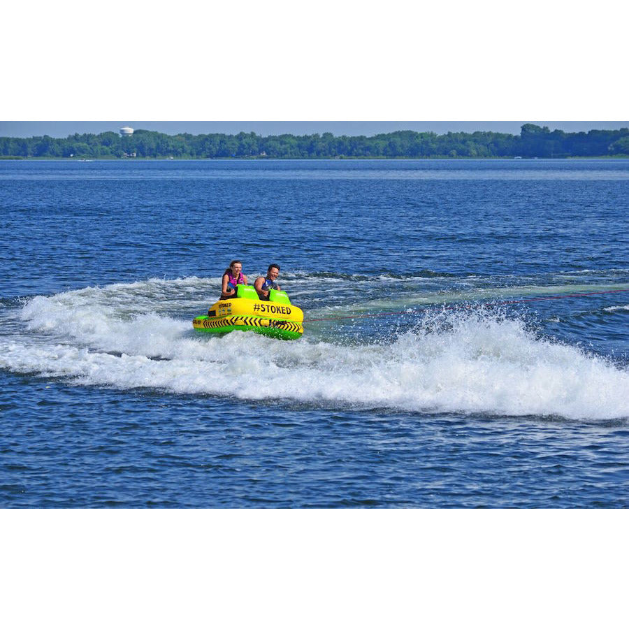 Green and yellow Rave #Stoked 2 Person Towable Boat Tube black seats for 2 riders, sky view.