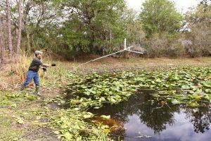 A man uses his Jenlis&nbsp;Weed Razer Pro Lake&nbsp;and Pond Weed Cutter to clear a pond of plants.