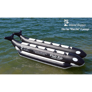 Above top, front side view of the Island Hopper 10 Person Banana Boat Tube Whale Ride sitting on the water.  Features side by side seating for 10 people on 2 inflatable pontoons that are made to look like a killer whale.  Black and white design, color picture.
