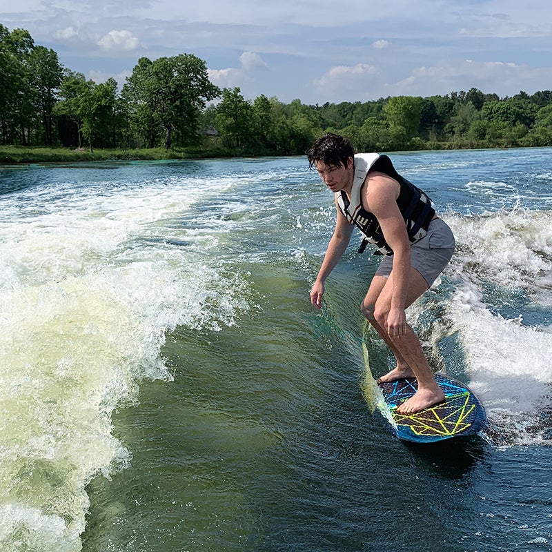 A person in the lake, riding the rave wake surf board.