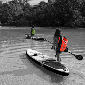 This shows the orange and yellow PRO-VIS Backpack on each women's backs on their way to paddleboarding.
