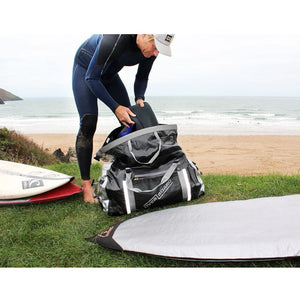 This is an image of a person at the beach, using the Overboard Pro-Sports Waterproof Duffel Bag.