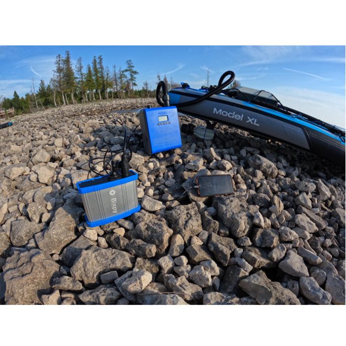 PP-77-AP 12V Outdoor Power Bank in action on a rocky terrain connecting to an electric pump while a smartphone is connected and charging at the same time.
