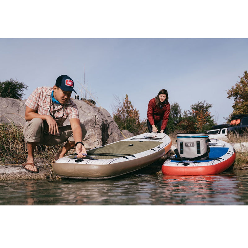 El Capitan 11&#39;6&quot; Inflatable SUP beside the water with 2 people attempting to use the paddleboard.