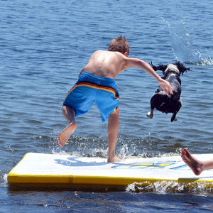 Aqua Mat Deluxe 20' on the water with a kid and dog jumping off of it.